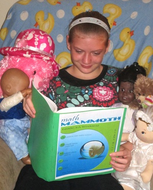 child studying Math Mammoth grade 3-A student book, with dolls child studying Math Mammoth grade 3-A student book, with dolls